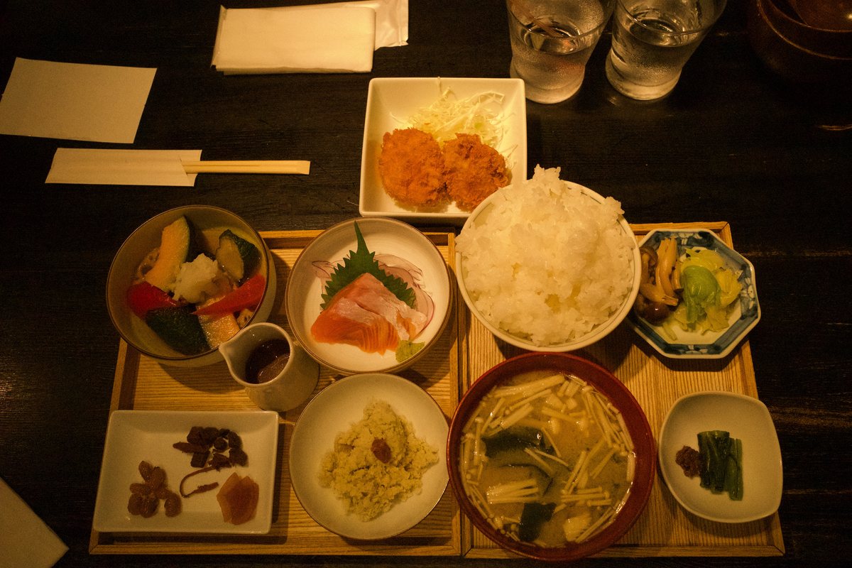 山盛りのご飯、お味噌汁、お刺身、野菜の煮物、おから、お漬物、おひたし、揚げ物が並んだお盆